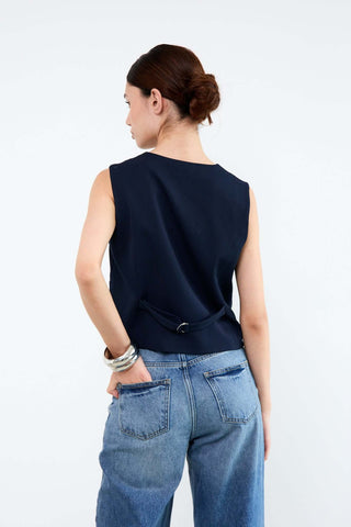 Woman wearing a navy sleeveless top and blue jeans