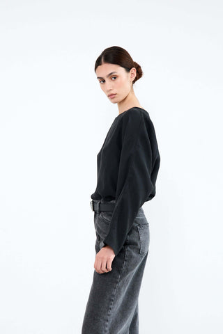 Woman wearing a black sweater and gray jeans 