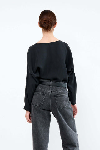 Person wearing a black top and gray jeans from behind 