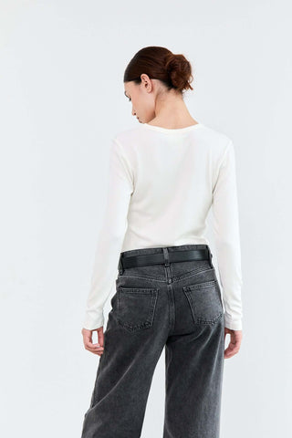 Person wearing a white long-sleeve shirt and dark jeans