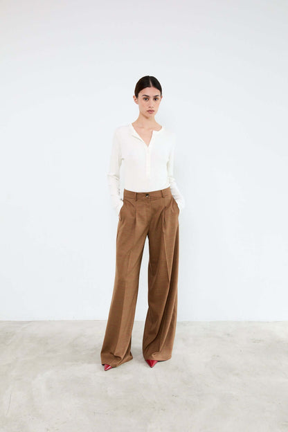 Woman wearing a white blouse and brown pants 