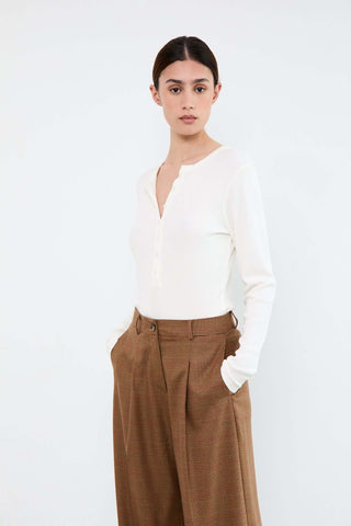 Woman wearing a white blouse and brown pants