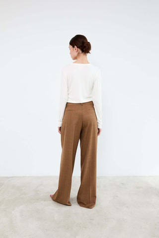 Person wearing a white top and brown pants