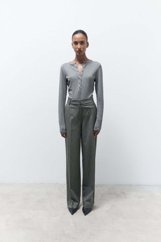 Person wearing a gray long-sleeve top and wide-leg pants on a white background