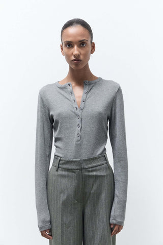 Woman wearing a gray long-sleeve top and gray pants on a white background