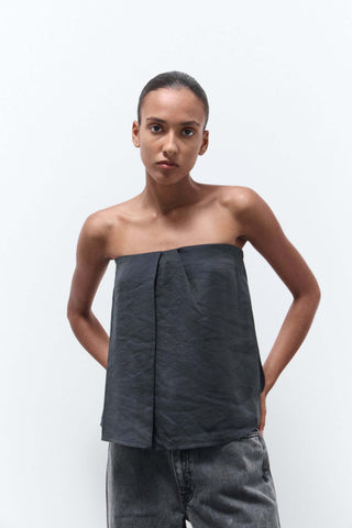 Woman wearing a strapless dark gray top and jeans on a white background