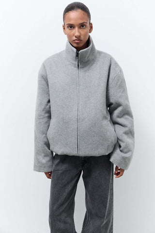 Person wearing a gray zip-up jacket and pants 