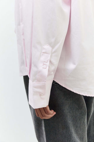 Close-up of a person wearing a light pink shirt and dark gray pants on a white background