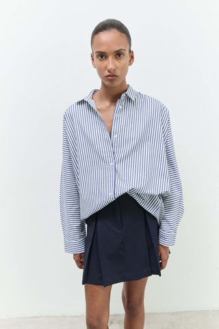 Person wearing a striped shirt and black skirt against a white background