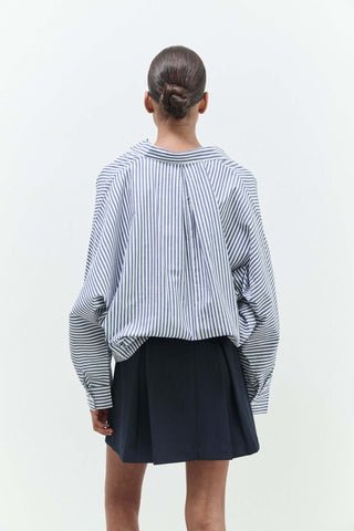 Person wearing a black and white striped shirt with a navy skirt on a white background