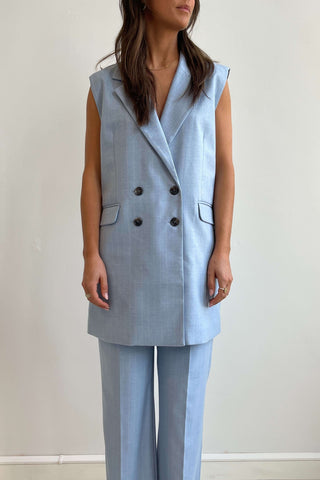 Woman wearing a light blue suit with a vest and pants