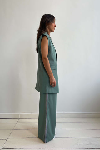 Woman wearing a green sleeveless top and pants