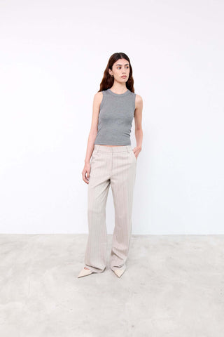 Woman wearing a gray sleeveless top and beige pants