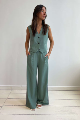 A person wearing wide-leg green pants and a matching green sleeveless top with a V-neckline.