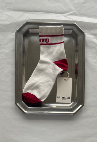 White sock with red accents on a metallic tray against a white background
