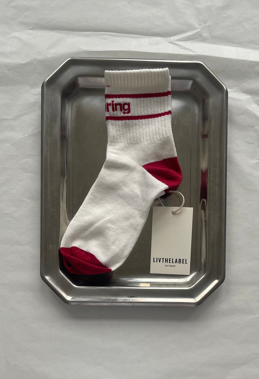 White sock with red accents on a metallic tray against a white background