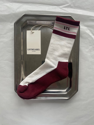 Maroon and white sock with a tag on a metal tray