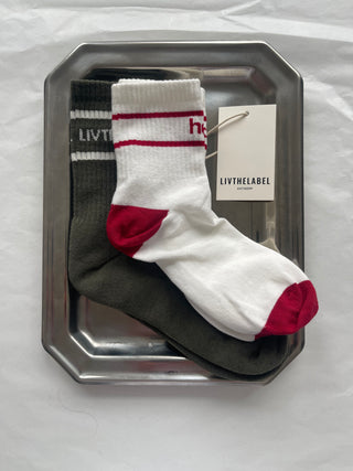 White sock with red accents on a metal tray with 'LIVTHELABEL' tag
