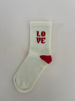 A pair of white socks with the word 'LOVE' printed in red heart shape on the side, also showing a red heel.
