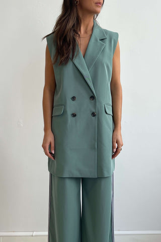 Woman wearing a green sleeveless blazer and pants