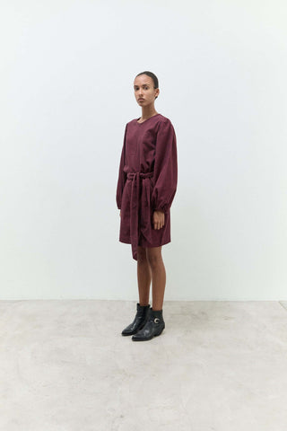 Person wearing a burgundy dress with a white background