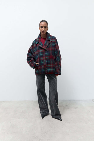 Model wearing oversized plaid jacket in dark tones