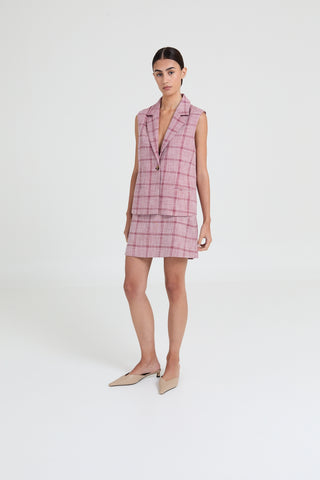 Woman wearing a pink plaid dress against a white background