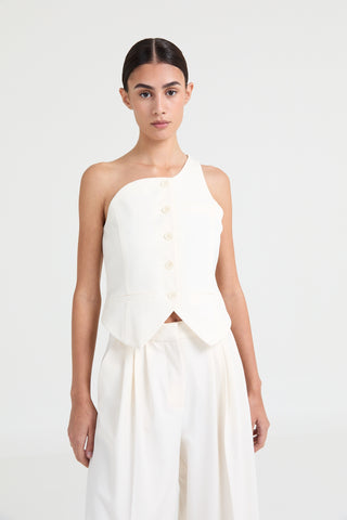 Woman wearing a white one-shoulder dress on a plain background