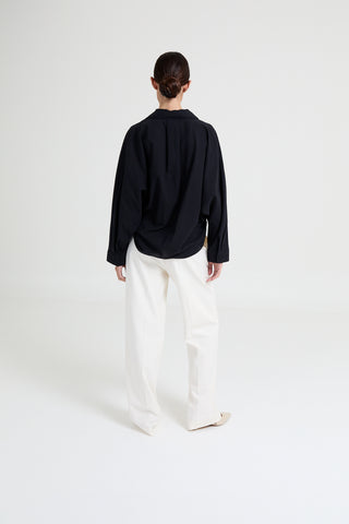 Person wearing a black shirt and white pants on a white background