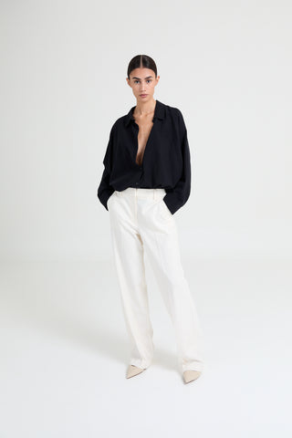 Person wearing a black shirt and white pants on a white background