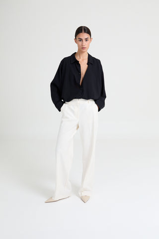 Person wearing a black shirt and white pants on a white background