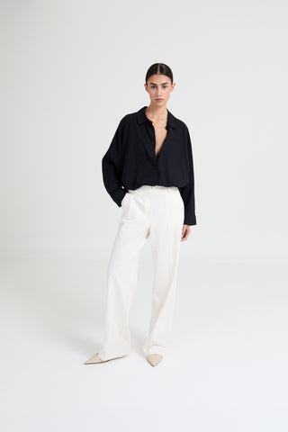 Person wearing a black shirt and white pants on a white background