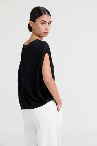 Woman wearing a black top and white pants on a white background