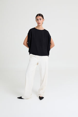 Person wearing a black top and white pants on a white background
