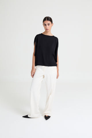 Person wearing a black top and white pants on a white background
