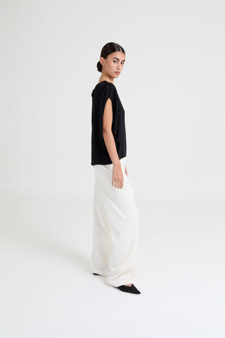 Person wearing a black top and white pants on a white background