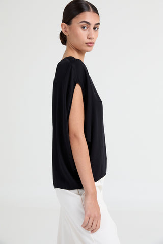 Woman wearing a black top and white pants on a white background