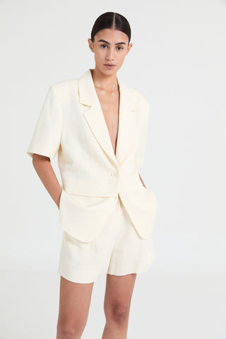 Woman wearing a cream-colored blazer dress against a white background
