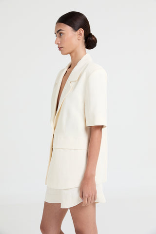 Woman wearing a white blazer and skirt set on a white background