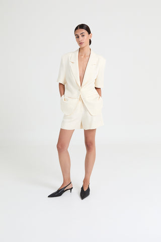 Woman wearing a cream blazer dress with a white background