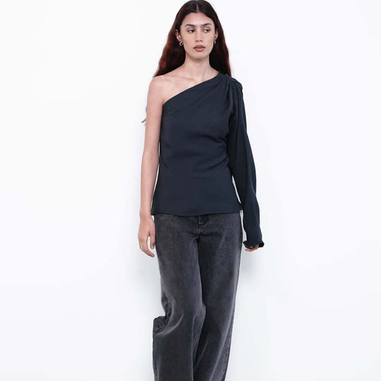 Model wearing black one-shoulder top with wide-leg jeans