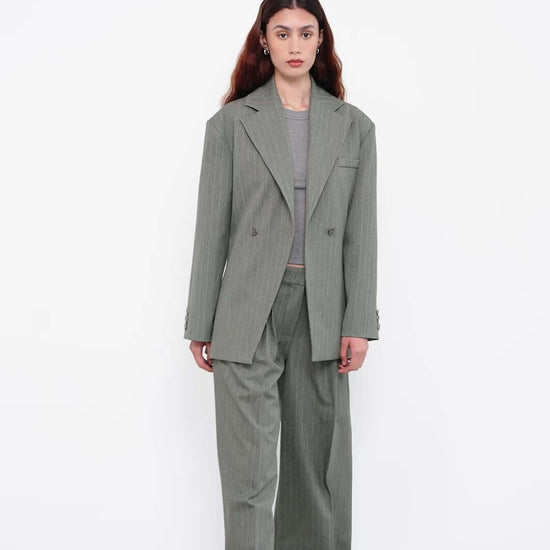 Model in oversized green pinstripe suit with wide-leg trousers