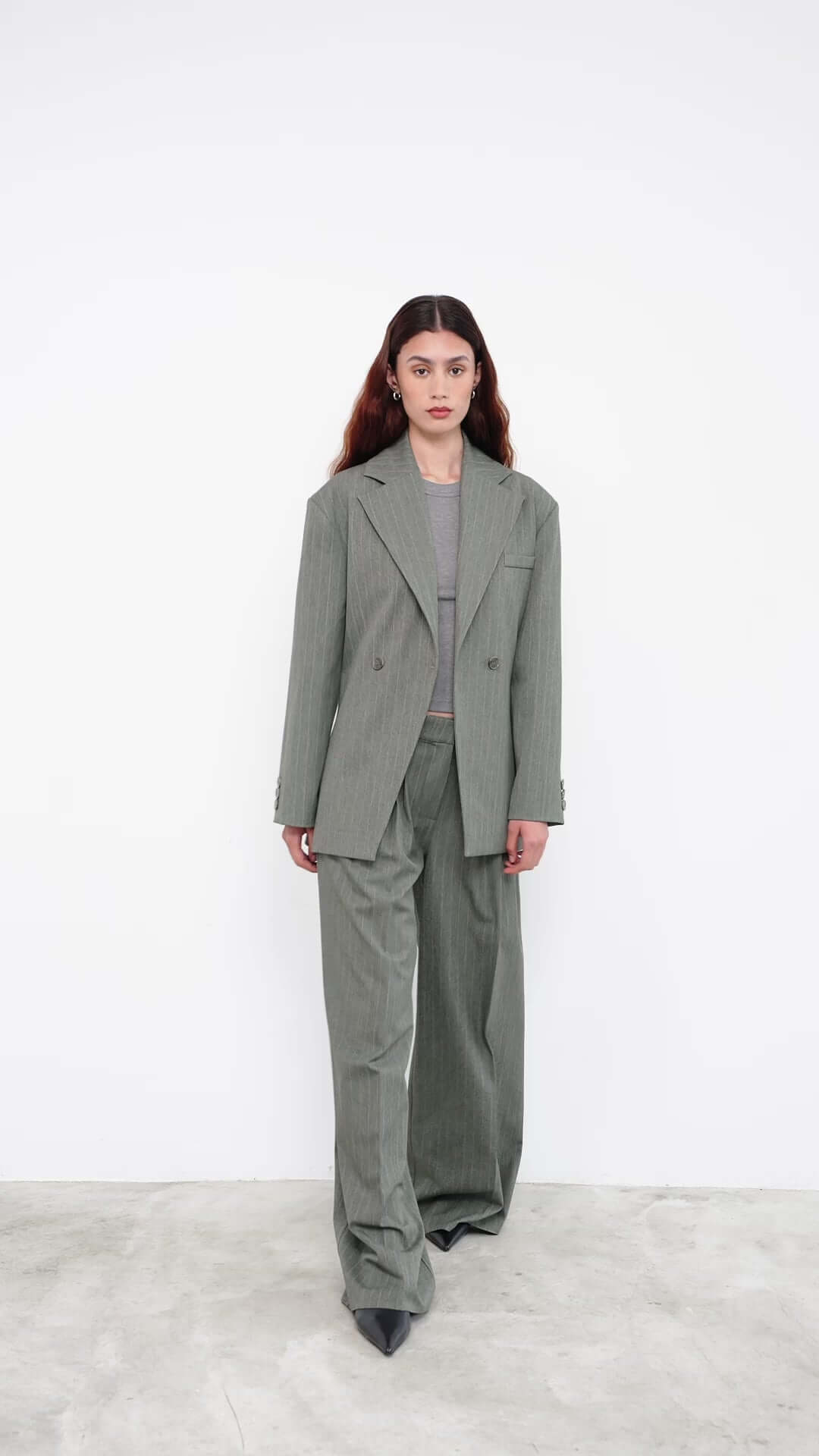 Model in oversized green pinstripe suit with wide-leg trousers