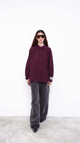 Model wearing black one-shoulder top with wide-leg jeans