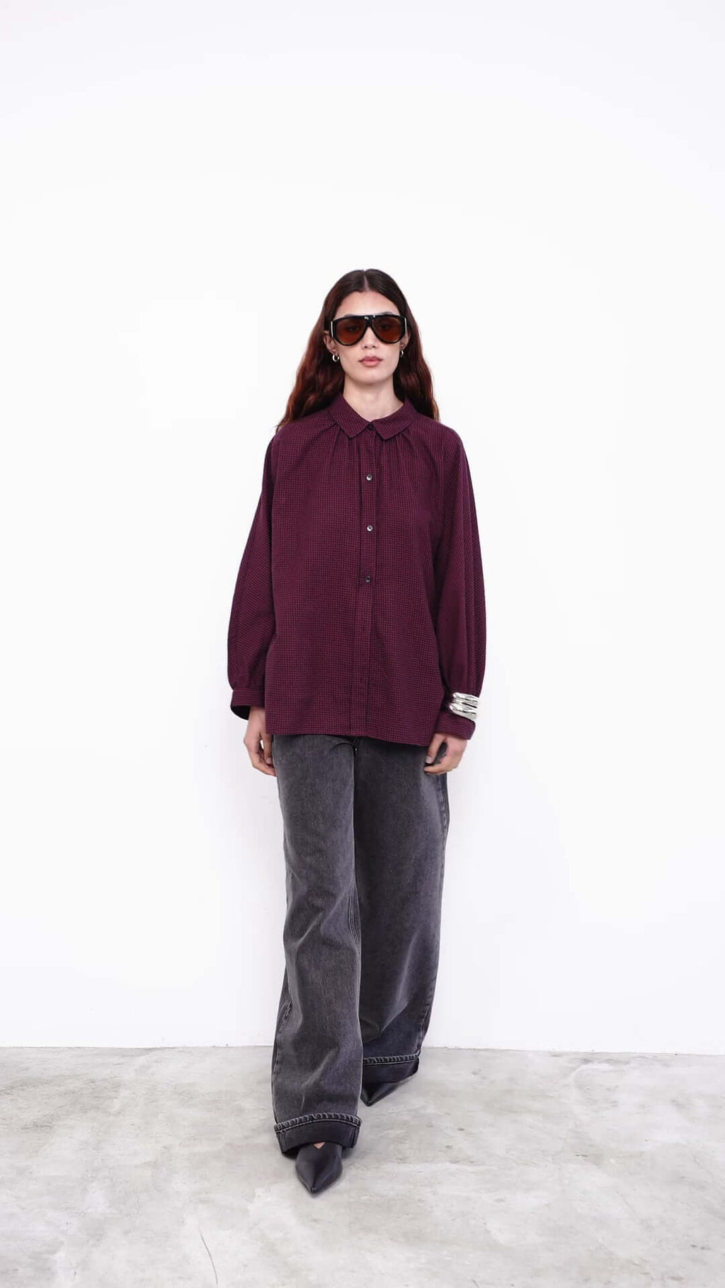 Model wearing black one-shoulder top with wide-leg jeans