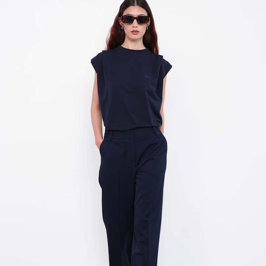 Model wearing navy sleeveless top and wide-leg trousers