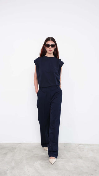 Model wearing navy sleeveless top and wide-leg trousers