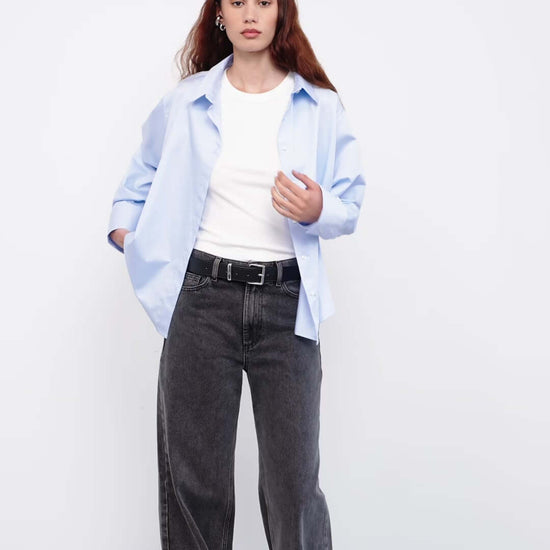 Model wearing light blue shirt with white tee and wide-leg jeans