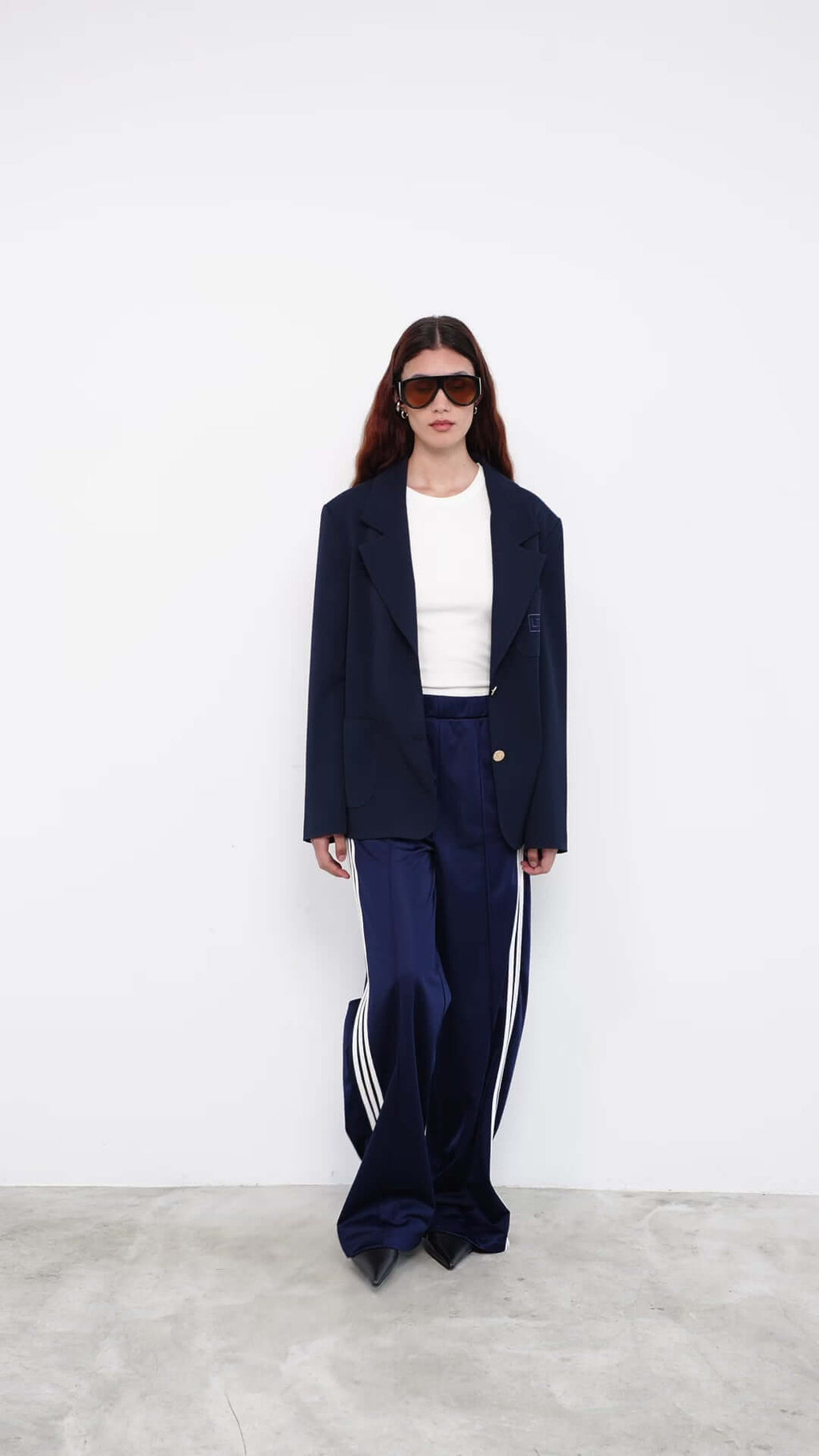 Model wearing navy blazer with satin track pants and white top